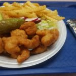 A plate featuring avocado slices, French fries, and chicken, offering a delicious and satisfying meal